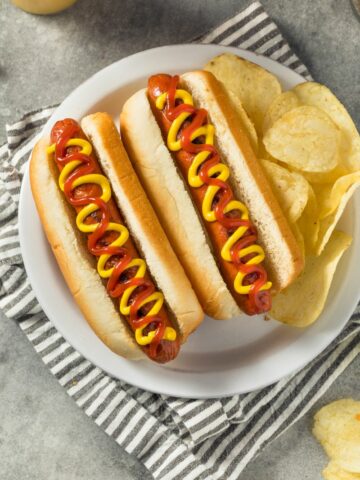hot dogs with ketchup and mustard in a bun on a plate