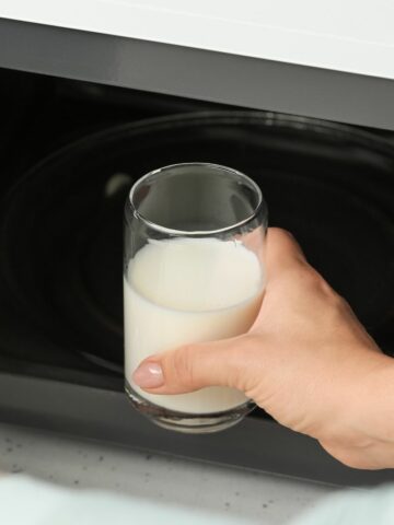 Glass cup with milk being put into the microwave